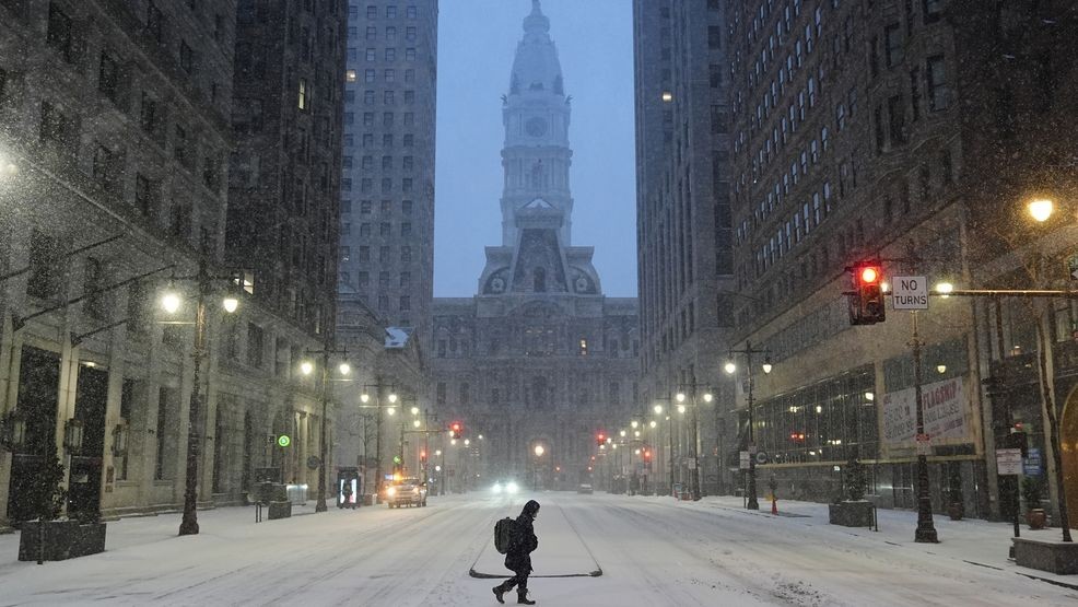 A person walks across a street during a winter storm in Philadelphia, Sunday, Jan. 25, 2026. (AP Photo/Matt Rourke)