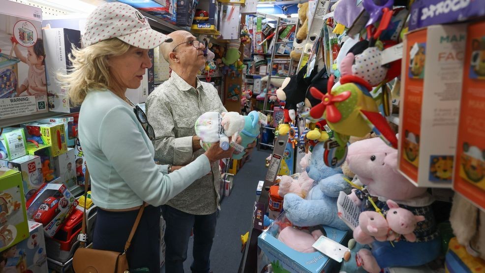 FILE - Hezzi Ramim (R) helps Linda Lynn Levy look for a toy in his A to Z Toys store on May 7, 2025, in Miami Beach, Florida. (Photo by Joe Raedle/Getty Images)
