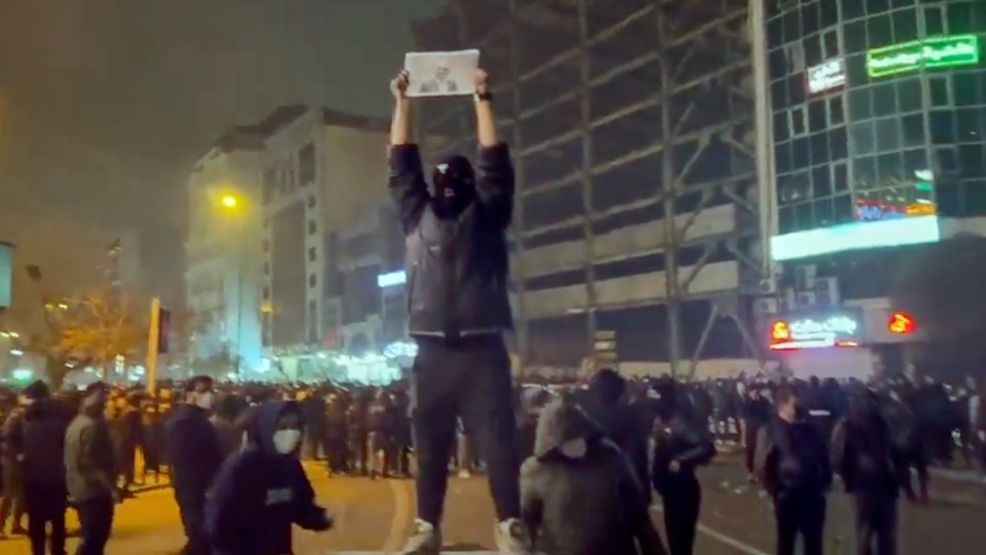 In this frame grab from video obtained by the AP outside Iran, a masked demonstrator holds a picture of Iran's Crown Prince Reza Pahlavi during a protest in Tehran, Iran, Friday, January. 9, 2026. (UGC via AP)