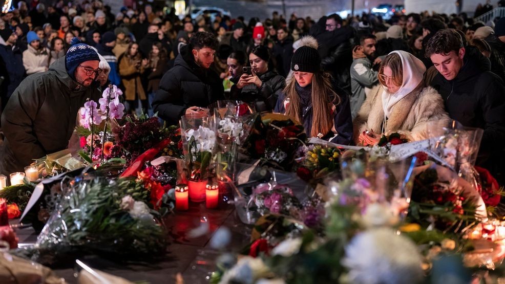 People lay flowers and light candles for the victims of the fire at the "Le Constellation" bar and lounge during New Year's celebration, in Crans-Montana, Switzerland, Thursday, Jan. 1, 2026. (Alessandro della Valle/Keystone via AP)