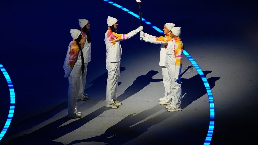 The Olympic torch is passed during the Olympic opening ceremony at the 2026 Winter Olympics, in Milan, Italy, Friday, Feb. 6, 2026. (AP Photo/Petr David Josek)