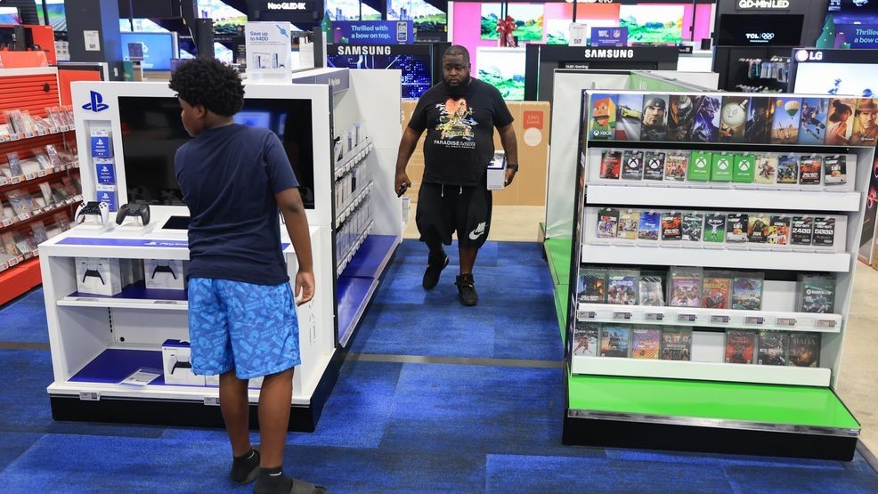 Robert Crockett and his son, Robert Crockett Jr. shop for last minute gifts to buy at a Best Buy store on December 23, 2025 in Miami, Florida. (Photo by Joe Raedle/Getty Images)