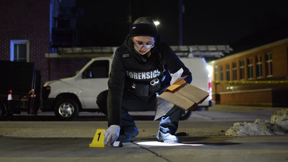 A crime lab technician examines a cartridge casing at a crime scene in east Baltimore on Saturday. (WBFF / Maggie Ybarra){ }
