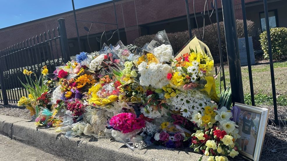 Flowers lie along a fence outside North Hall High School in Gainesville, Ga., on Monday, March 9, 2026. (AP Photo/Emilie Megnien)