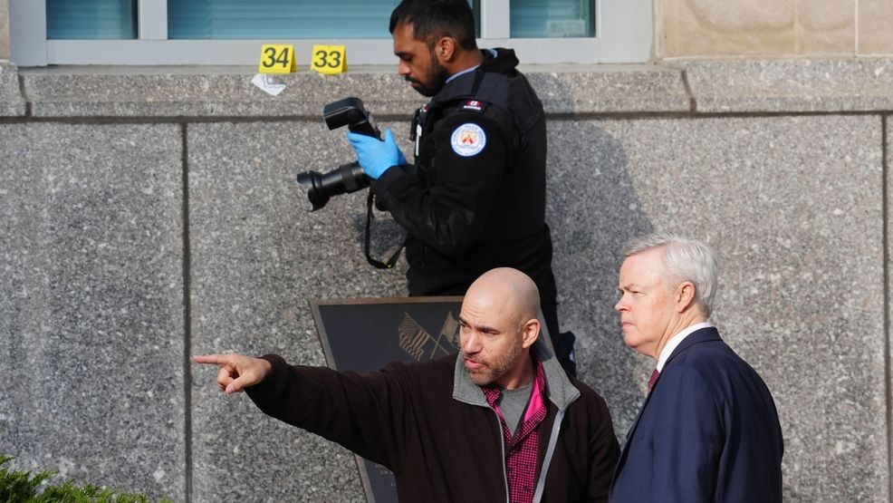 Consulate officials speak together as a Toronto forensic officer photographs bullet impact marks at the front U.S. consulate in Toronto on Tuesday March 10, 2026.  (Frank Gunn/The Canadian Press via AP)