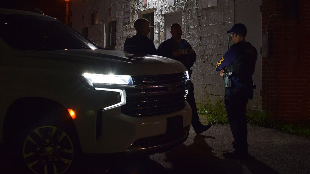 Auto theft detectives watch as a tow truck driver removes a wanted vehicle from behind a business in the 4800 block of Harford Road. (WBFF / Maggie Ybarra)