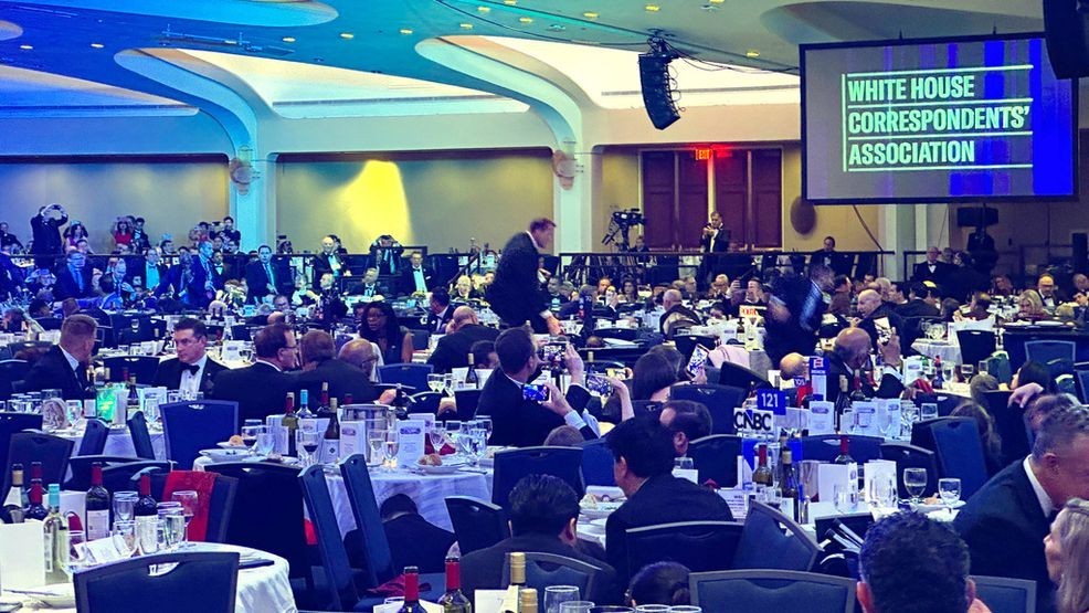 Guests take cover under tables after a shooting incident outside the ballroom during the White House Correspondents Dinner, Saturday, April 25, 2026, in Washington. (AP Photo/Alex Brandon)