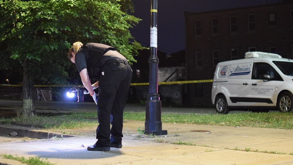 A crime lab technician searches for evidence of a shooting near the intersection of East Lombard Street and Lloyd Street on Saturday morning. (WBFF / Maggie Ybarra)