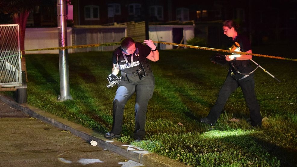 Crime lab technicians walk across the 2800 block of Elgin Avenue to get from one crime scene to another while collecting evidence of a shooting on Friday. (WBFF / Maggie Ybarra)
