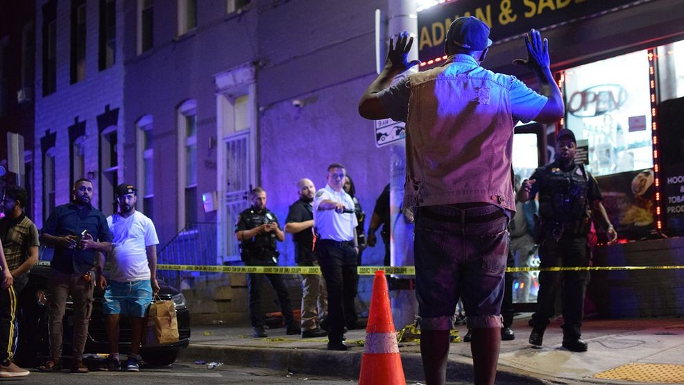 A man holds his hands up as he approaches the site of a shooting in the 1200 block of East Preston Street to show police that he poses no threat. (WBFF / Maggie Ybarra)