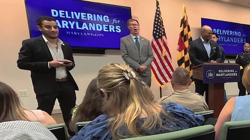 On Thursday, July 23, 2026, during the governor's "Delivering for Maryland" tour in Millersville, Md., Maryland Gov. Wes Moore's spokesperson, Ammar Moussa, left; Anne Arundel County Executive and Maryland Democratic Party chairman Steuart Pittman, center; and Moore, right, laughed off a question about whether Marylanders know who their governor is. (Steve Pierce/Spotlight on Maryland)