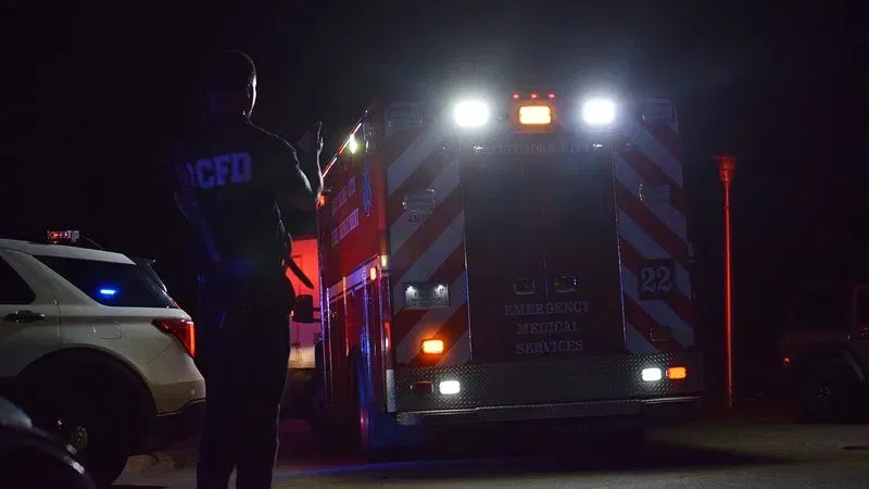 A first responder helps direct an empty ambulance away from a shooting site in Baltimore's Shipley Hill neighborhood on Saturday morning. (WBFF / Maggie Ybarra)