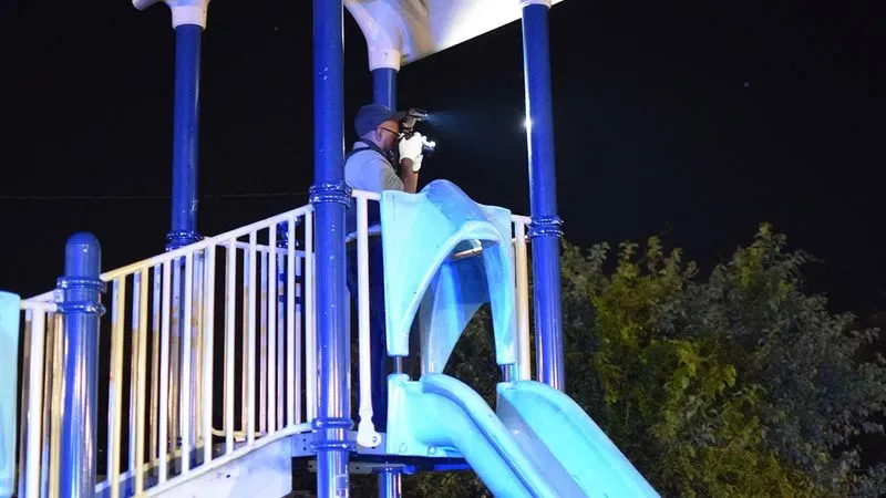 A crime lab technician takes a picture of a crime scene near a playground at the Cherry Hill Homes affordable housing community. (WBFF / Maggie Ybarra)