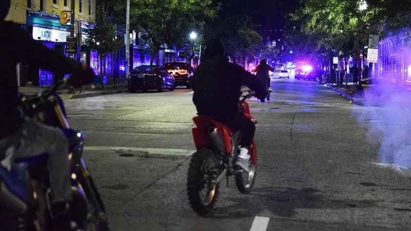 Dirt bike riders perform tricks next to a crime scene in Federal Hill on Sunday morning. (WBFF / Maggie Ybarra)