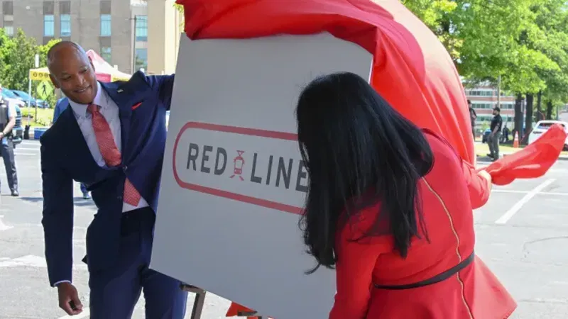 Gov. Wes Moore, left, and Lt. Governor Aruna Miller unveil the Red Line signage after announcing the decision to make the Red Line a light rail project. (Kevin Richardson/Baltimore Sun)