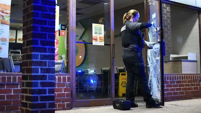 A forensics investigator searches for fingerprints on the door of a Subway sandwich shop following a string of commercial crimes in the Dundalk area on Saturday. (WBFF / Maggie Ybarra)