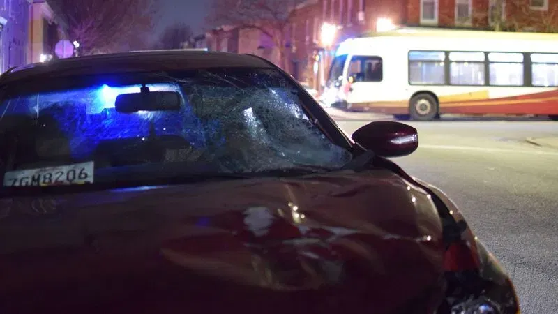 A patrol car sits behind a badly damaged vehicle parked in the 2300 block of Jefferson Street following a crash involving a pedestrian on Orleans Street. (WBFF / Maggie Ybarra)