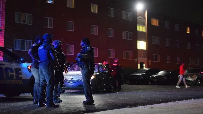 Officers discuss the search for evidence of gunfire at the Pedestal Gardens apartment complex in west Baltimore on Wednesday night. (WBFF / Maggie Ybarra)